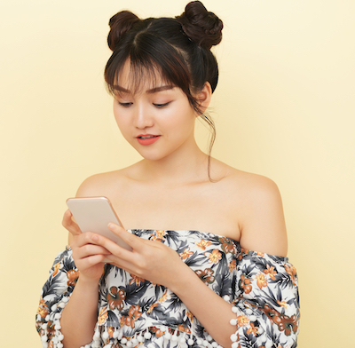 Pretty,Trendy,Asian,Woman,With,Hair,Buns,Surfing,Smartphone,On