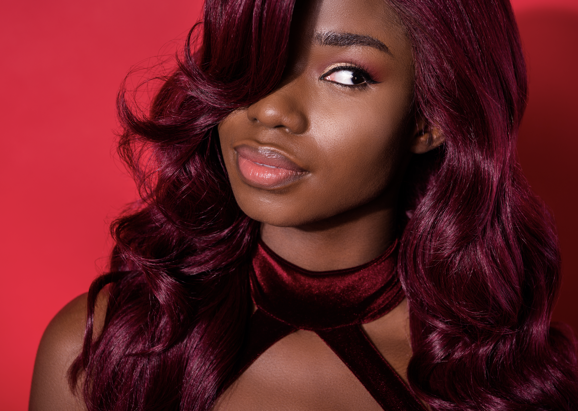 Woman with dark red hair against a red background