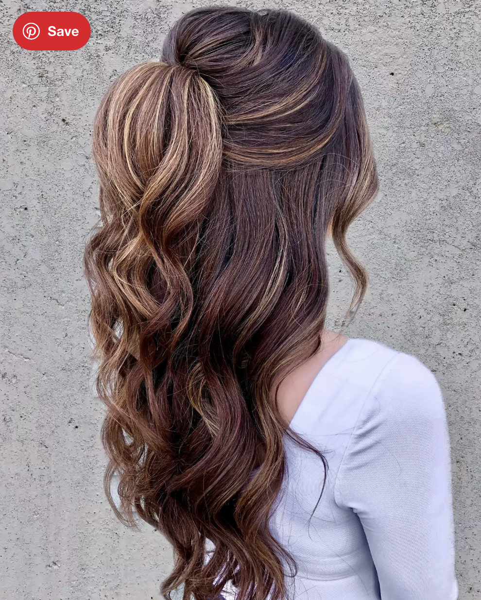 Woman with long brown hair styled in a flipped ponytail.